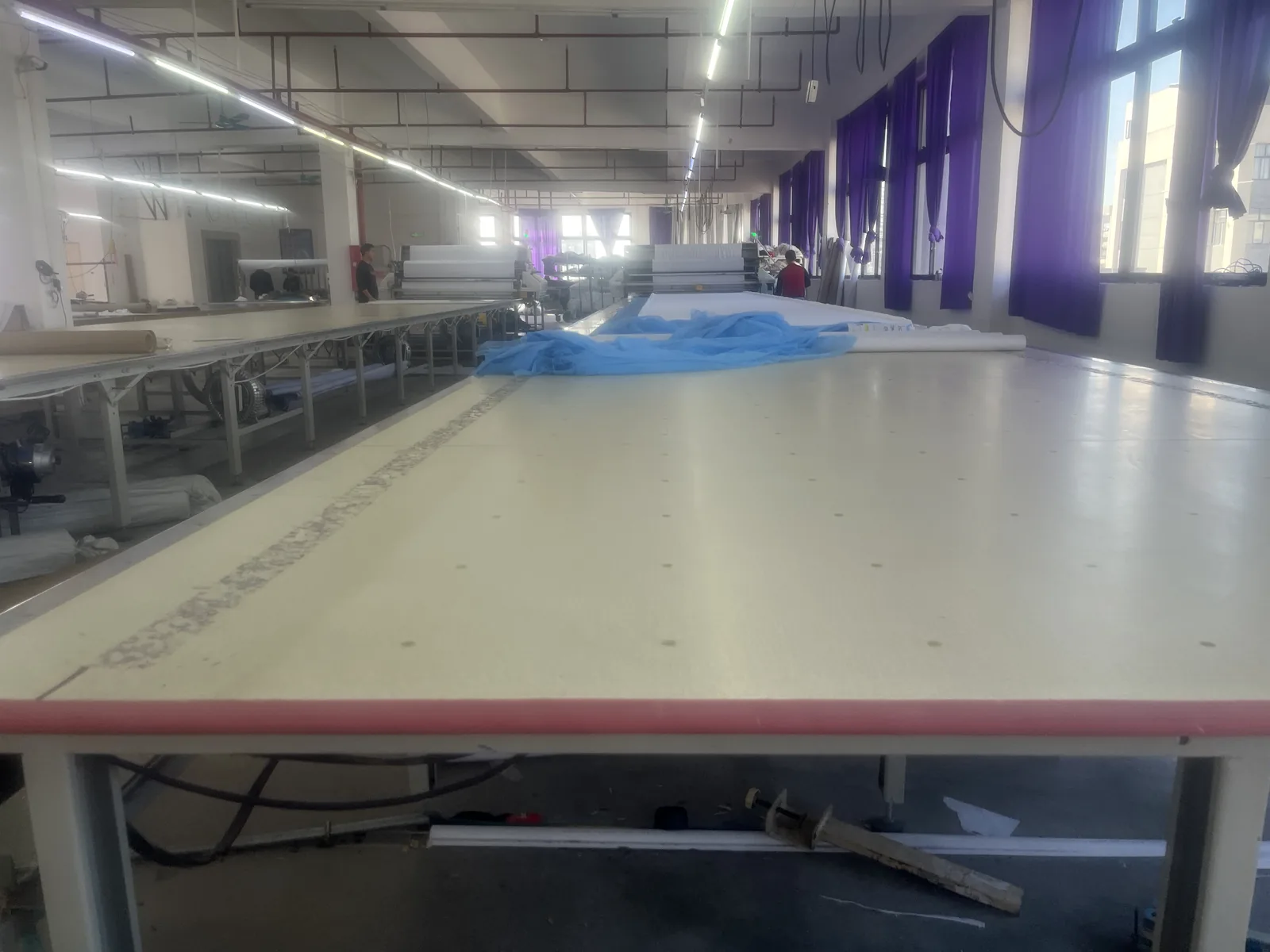 Large cutting table and workshop floor used for custom sportswear order preparation